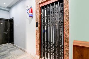 a black iron gate on a white wall with a fire extinguisher at Super Hotel O Narayana RN Tagore Hospital Formerly Lantern Guest House in Jādabpur +32 photos