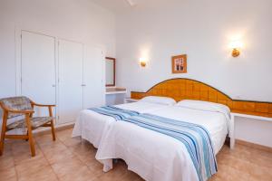 a bedroom with a large white bed and a chair at Apartamentos Sol Ponent in Cala Blanca +193 photos