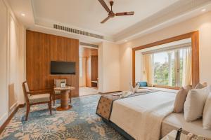 a bedroom with a bed and a desk and a television at The India Benares in Varanasi