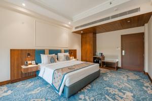 a bedroom with a large bed and a bathroom at The India Benares in Varanasi