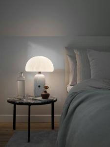 a lamp on a table next to a bed at Historic Vipp House From 1775 In Søllested in Søllested