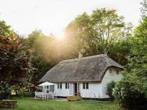 a white cottage with a thatched roof in a field at Historic Vipp House From 1775 In Søllested in Søllested