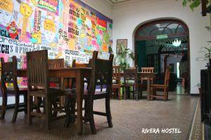 a dining room with a table and chairs and a wall at Rivera Hostel Córdoba in Cordoba