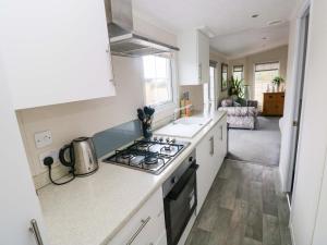a kitchen with a stove top oven next to a sink at Meadows Farm Lodge in Swansea +18 photos