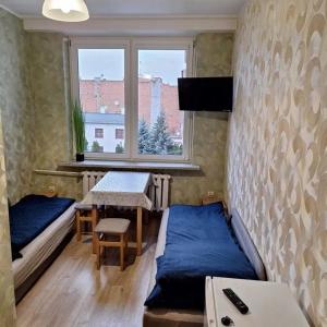 a room with a bed and a table and a window at Hostel Włocławek in Włocławek