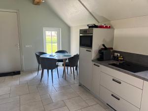 a kitchen with a table and chairs and a kitchen with a counter at De Dagloner in Nieuwlande