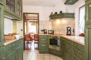 a kitchen with green cabinets and a dining room at Fischerhaus am Moosbach mit Sauna in Mietenkam