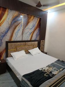 a bedroom with a large bed with a painting on the wall at Gita Raman Palace in Ayodhya