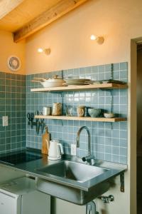 a kitchen with a sink and blue tiles at Ocean view cabin in Nanjo
