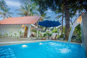 a pool with an umbrella next to a house at Ceylon Princes Villa in Ahangama