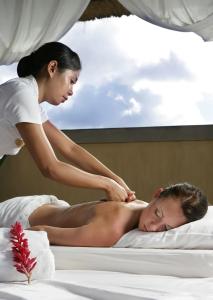 a woman giving a man a massage in a bed at The Beverly Hills Bali Villas Resort in Jimbaran