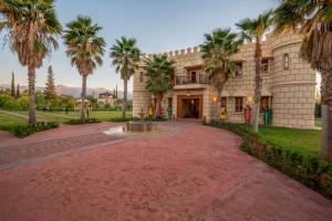 a large building with palm trees in front of it at Atlas Castle Marrakech in Marrakesh