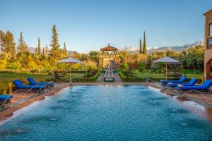 a swimming pool with blue chairs and a gazebo at Atlas Castle Marrakech in Marrakesh