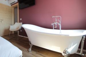 a white bath tub in a room with a purple wall at Villa Valdobbiadene Pool Spa in Valdobbiadene