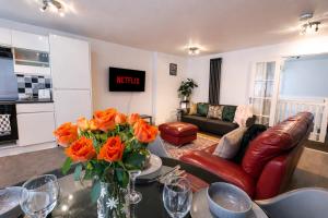 a living room with a vase of orange flowers on a table at Spacious, Modern and stylish three bedroom home , perfect for work , leisure and contractors ,5 mins walk to Newcastle city Center, Newcastle stadium and Newcastle University, Free parking Fast WiFi, conveniently located both short stay and long stays in Newcastle upon Tyne