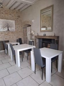 a dining room with white tables and chairs and a fireplace at Maison d'Eusébia in Château-Chalon