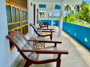 a porch with chairs and tables on a house at Paradise Bay Hotel in Arugam Bay