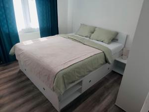 a white bed in a bedroom with blue curtains at Dom priamo pri rieke in Opatovce nad Nitrou