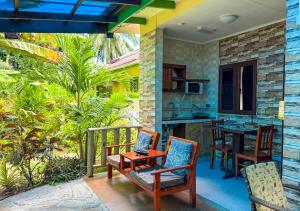 a patio with chairs and a table and a kitchen at Buisson Guesthouse in La Digue