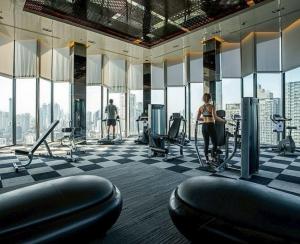 a woman exercising in a gym with a view of the city at Thong Lor condo Next to BTS in Bangkok
