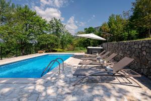 a group of chairs and an umbrella next to a swimming pool at Villa Rocco in Kozljak