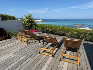 a deck with chairs and a table and the ocean at Maison les pieds dans l'eau - de 2 à 6 personnes in Lumio