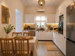 a kitchen with white cabinets and a table and chairs at Evanthia's House in Arianá