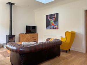 a living room with a leather couch and a yellow chair at Cottage 503 - Leenane in Leenaun