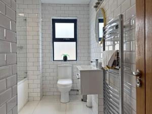 a bathroom with a toilet and a sink and a window at Cottage 503 - Leenane in Leenaun +25 photos