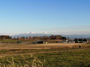 ein Feld mit schneebedeckten Bergen im Hintergrund in der Unterkunft あらさんち in Asahikawa