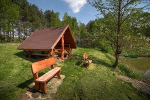a wooden pavilion with a bench in the grass at Zacisze nad Sanną in Annopol