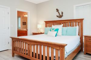 a bedroom with a large wooden bed with blue pillows at Five on the Beach by Pristine Property Vacation Rentals in Cape San Blas +72 photos