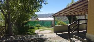 a house with a gate and a tree in a yard at La Nave del Olvido- Cabaña Potrerillos in Potrerillos