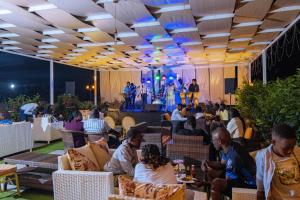 Eine Gruppe von Menschen sitzt in einem Restaurant mit einer Bühne in der Unterkunft Allison Hotel in Jinja + 179 Fotos