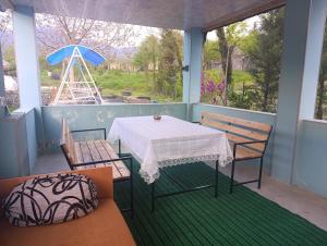 a porch with a table and chairs and an umbrella at Zaqatala-Car riverside cottage in Zaqatala