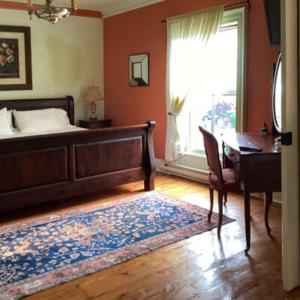 a bedroom with a bed and a desk and a window at Mariner King Inn in Lunenburg