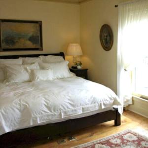 a bedroom with a white bed and a window at Mariner King Inn in Lunenburg