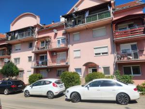 three cars parked in front of a pink building at Stan na dan Moonlight Panonija in Inđija