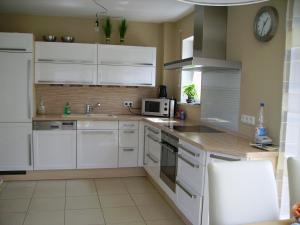 a kitchen with white cabinets and a clock on the wall at Wiflinger Graben Einfamilienhaus in Wörth