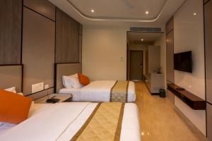 a hotel room with two beds and a television at Fortune Village Hotel in Kundapur +9 photos