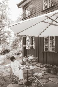 a woman sitting at a table under an umbrella at Badhotellet Villa Berg in Norrtälje +25 photos