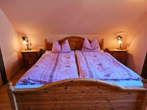 a bedroom with a wooden bed with pink sheets and pillows at Ferienhäuser Harmonie I & II in Burg Kauper +68 photos