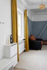 a living room with yellow curtains and a couch at Skala Hostel in Almaty