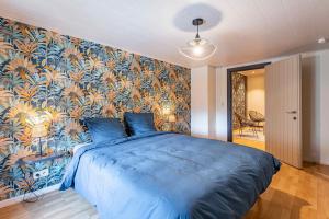 a bedroom with a blue bed with a colorful wall at Le charron in Bièvre