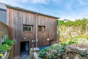 a wooden building with a door in a garden at Le charron in Bièvre