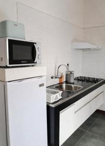 a kitchen with a microwave and a sink at Résidence Marotia in Antananarivo