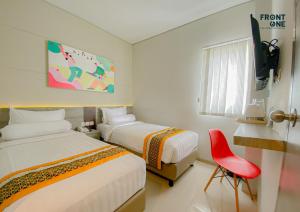 a hotel room with two beds and a red chair at Front One The Andia Boyolali in Boyolali