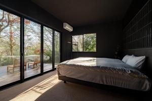 a bedroom with a bed and large glass windows at MUSUBI Hakone in Sengokuhara