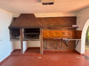 a room with a brick wall with a desk and a table at Hueso cue 105 in Paso de la Patria +3 photos