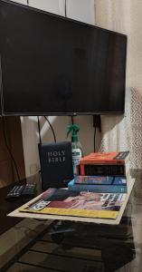 a pile of books sitting on a table with a tv at GLJ Apartment in Ormoc
